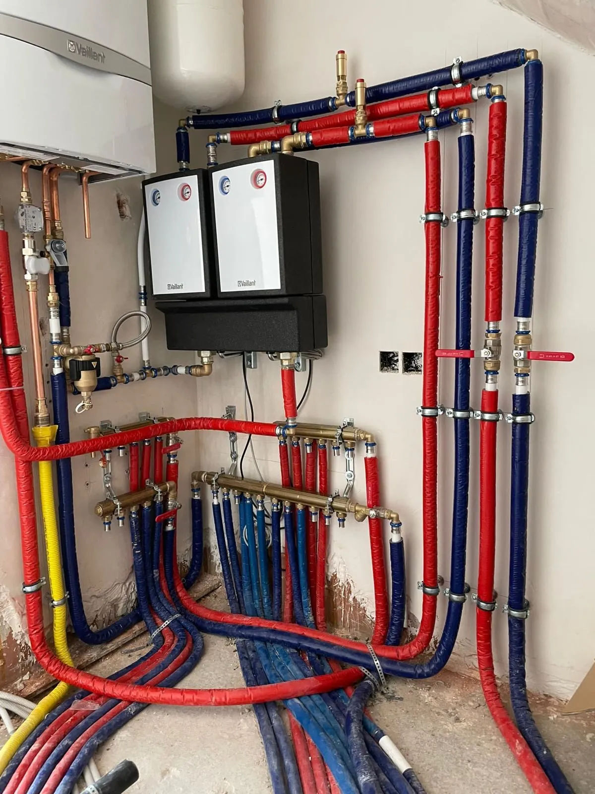 Rode en blauwe verwarmingscollectoren met een gasketel, geplaatst door HS Concept, loodgieter en chauffagist in Aalst