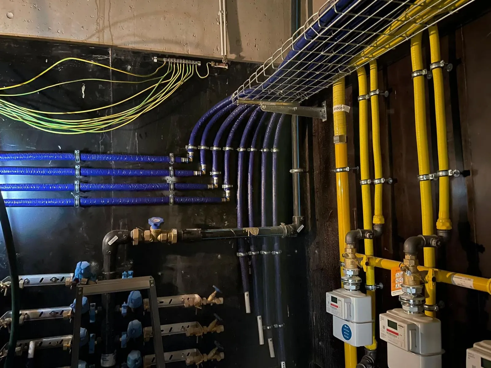 Technische ruimte met gasleidingen, gasmeters en waterleidingen in een appartementsgebouw, uitgevoerd door HS Concept in Aalst